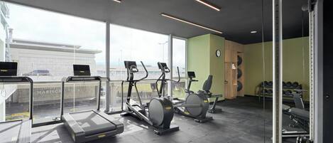 Un gimnasio con cintas de correr, elípticas y pesas libres.
