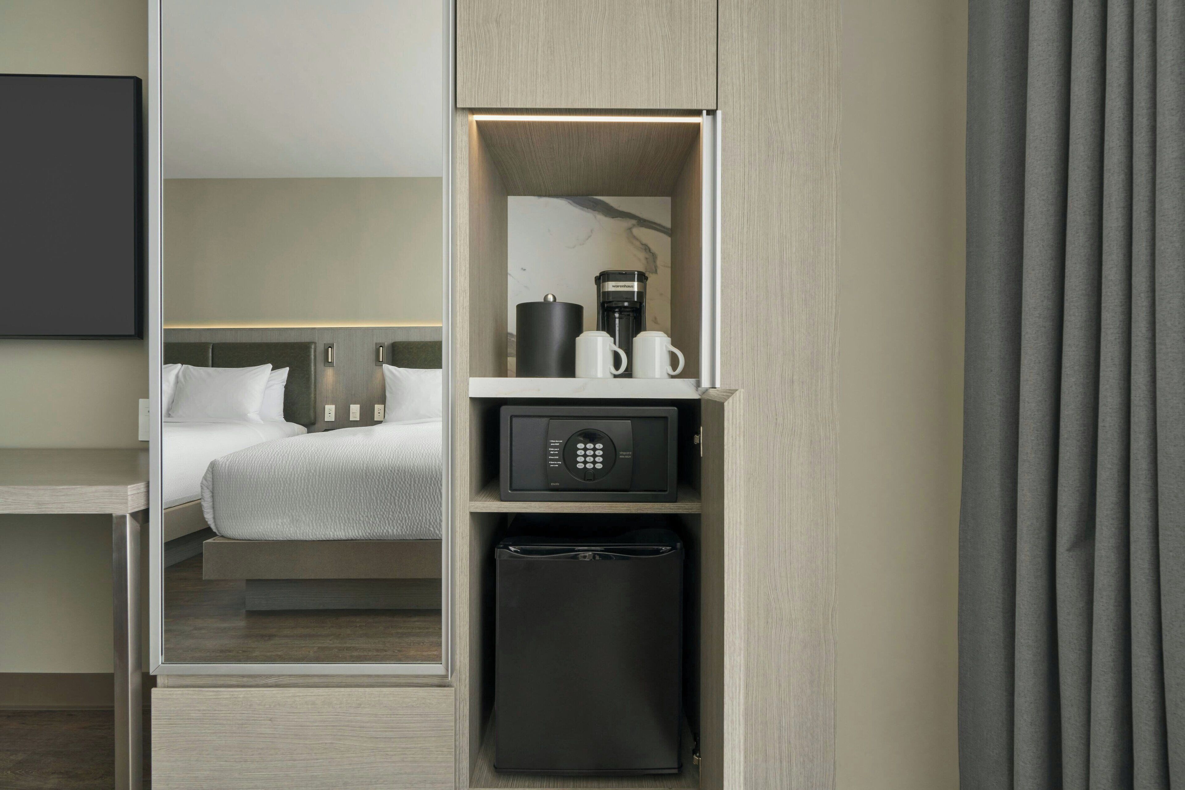 Una habitación de hotel con cama, minibar y cafetera.