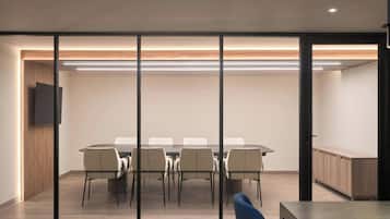 A conference room with a long table, chairs, and a TV on the wall.