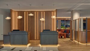Una zona de recepción moderna con dos mostradores, paneles de madera e iluminación colgante.