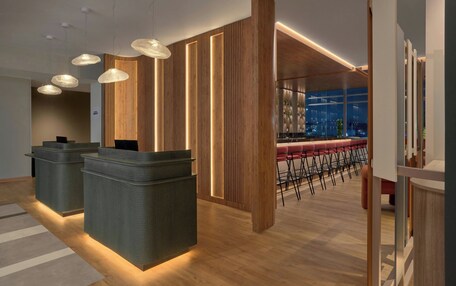 A modern reception area with a bar and seating area, featuring wooden accents and contemporary lighting.
