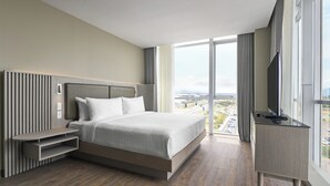 Una habitación de hotel moderna con una cama grande, un televisor y vistas a la ciudad.