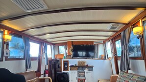 Um interior acolhedor com sofá, cadeiras, uma mesinha e uma televisão em uma cabine de navio.