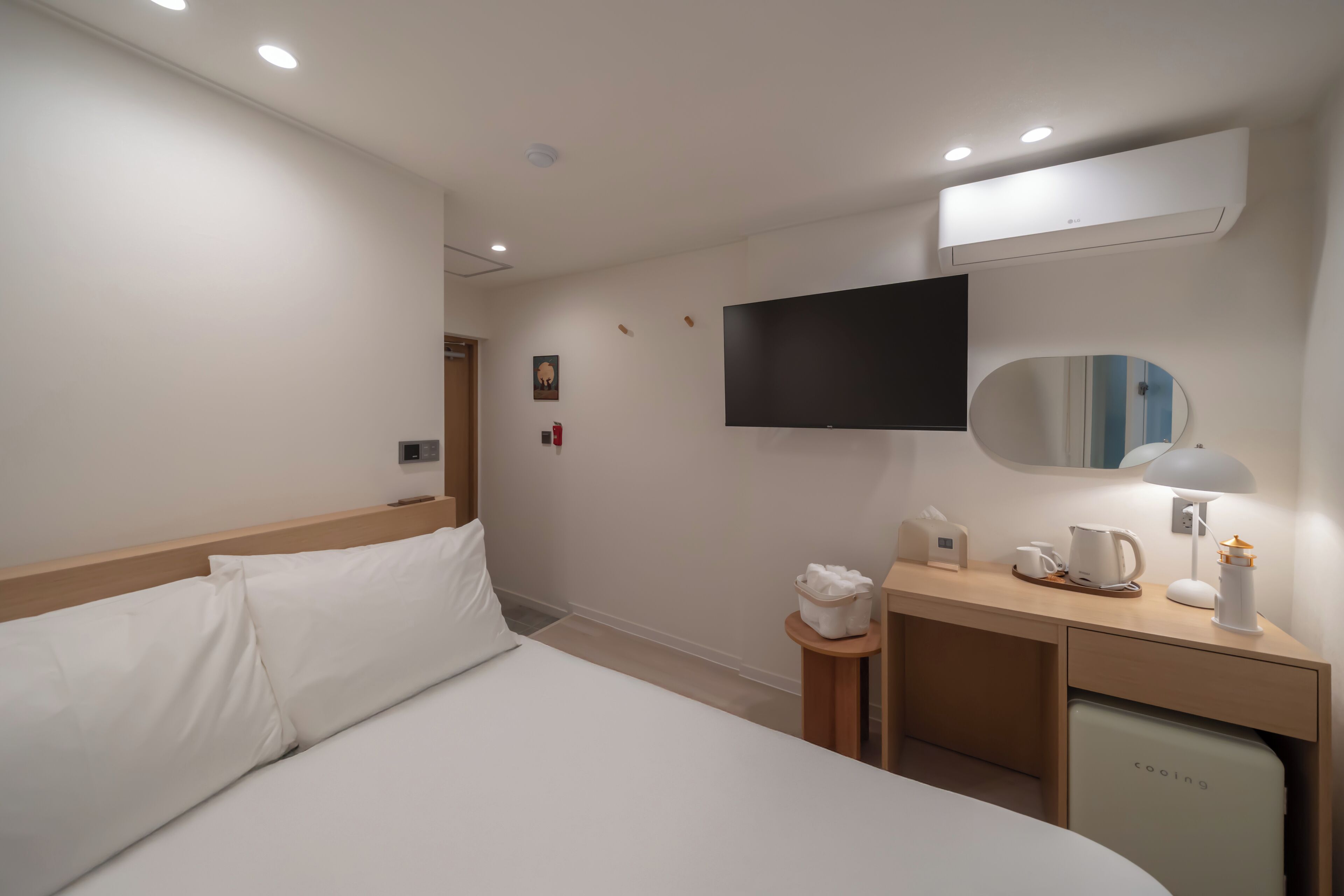 Une chambre d’hôtel équipée d’un lit, d’un bureau avec une lampe, d’une machine à café et d’un mini-réfrigérateur.