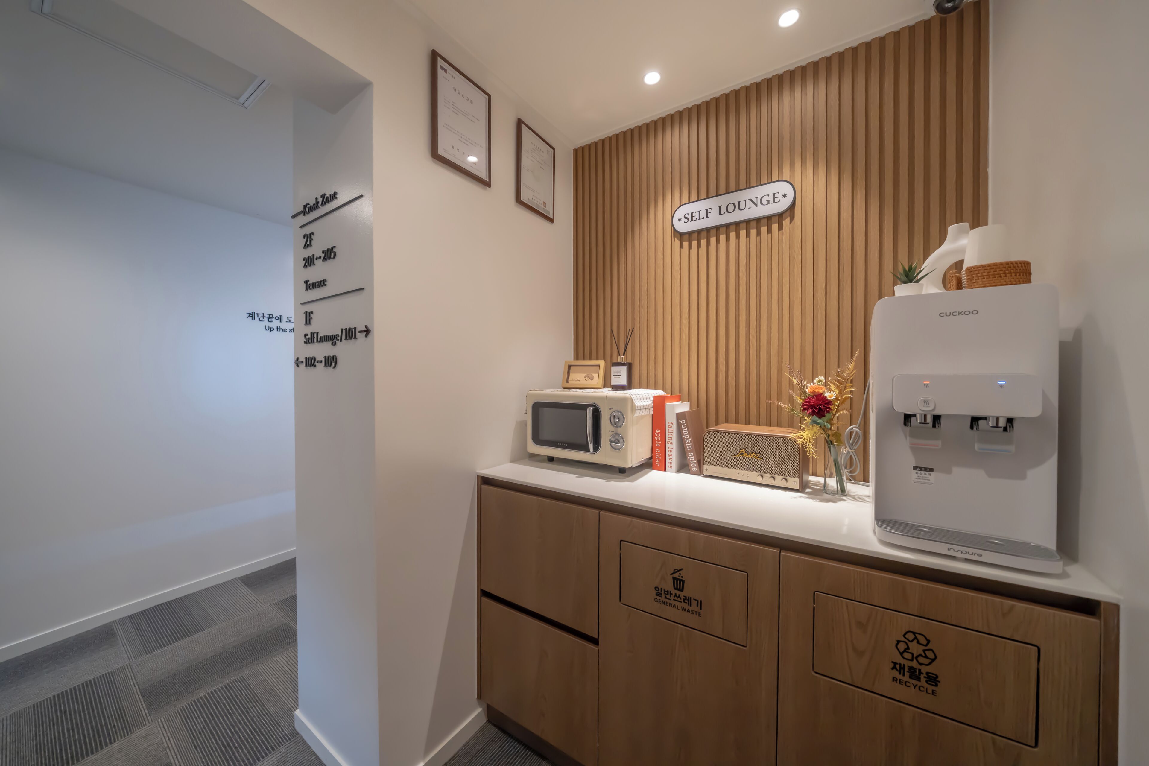 Espaço lounge com serviço próprio, incluindo micro-ondas, dispensador de água e contentor para reciclagem.