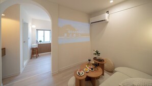 Een moderne hotelkamer met een zithoek, een bank en een projectiescherm aan de muur.