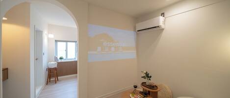 A modern hotel room with a dining area, a sofa, and a projection screen on the wall.