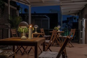 An outdoor patio area with wooden tables and chairs, potted plants, and decorative lamps. - Hotel DALSTAIR Seoul Jongno (Seoul)