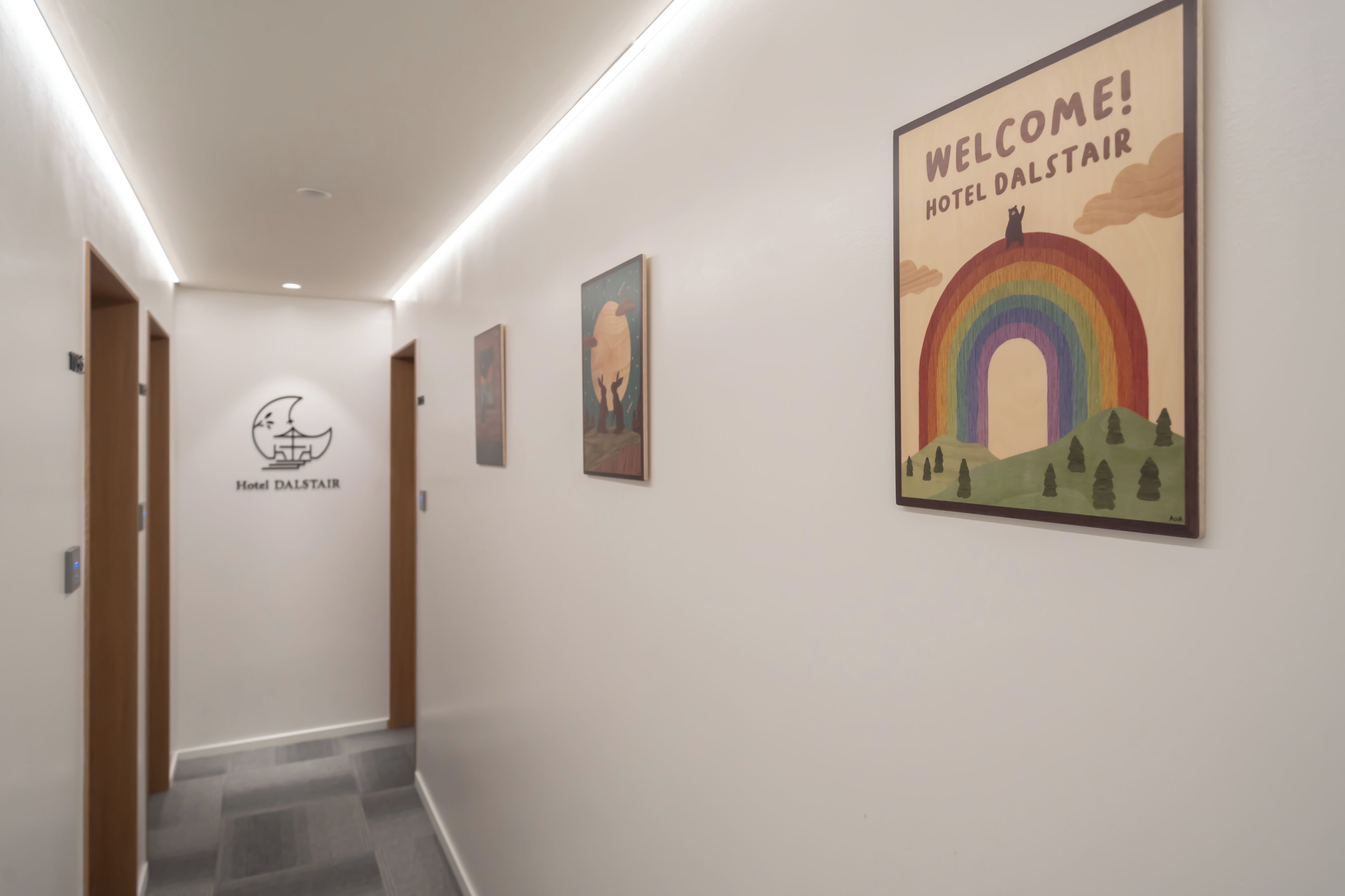 A hotel corridor with a sign reading "Hotel Dal Stair" and a welcome sign with a rainbow and trees.