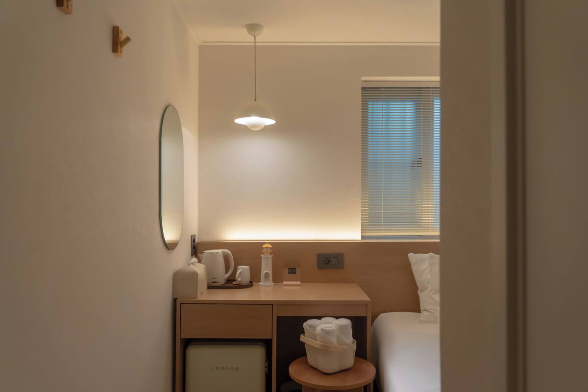 Une chambre d’hôtel avec un lit, une table de chevet et un petit coin salon.