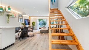 A modern interior with a wooden staircase, a dining area, and a view of the outdoors. - Selbourne Five - Two Bedroom Apartment, Sleeps 4 (Cape Town)