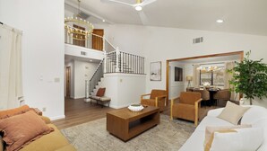 A spacious living area with a staircase, a dining area, and a large plant. - Lakeside Retreat Hot Tub, Fire Pit, 4BR/3BA (Victorville)