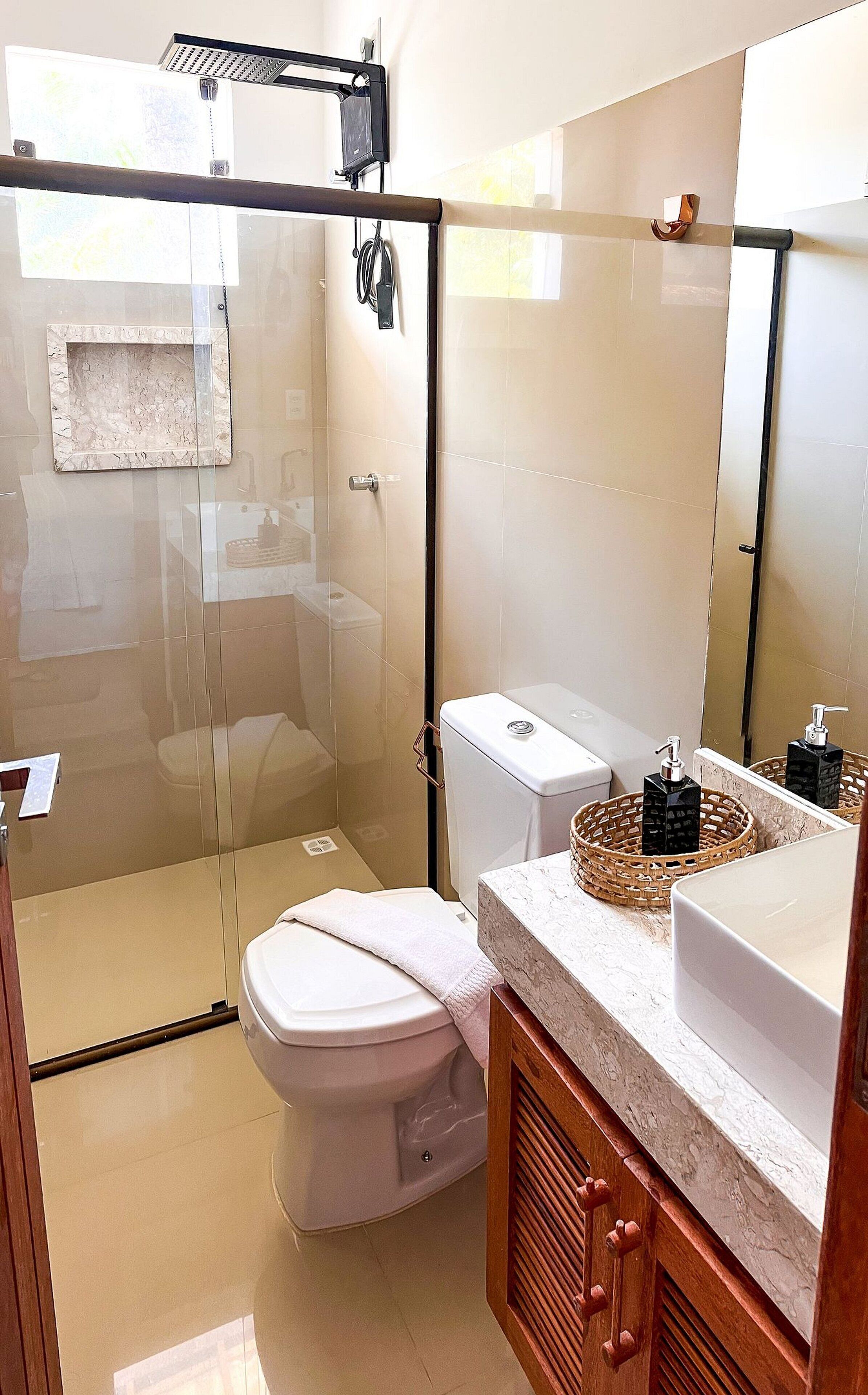 A modern bathroom with a glass-enclosed shower, a white toilet, and a vanity with a marble countertop.