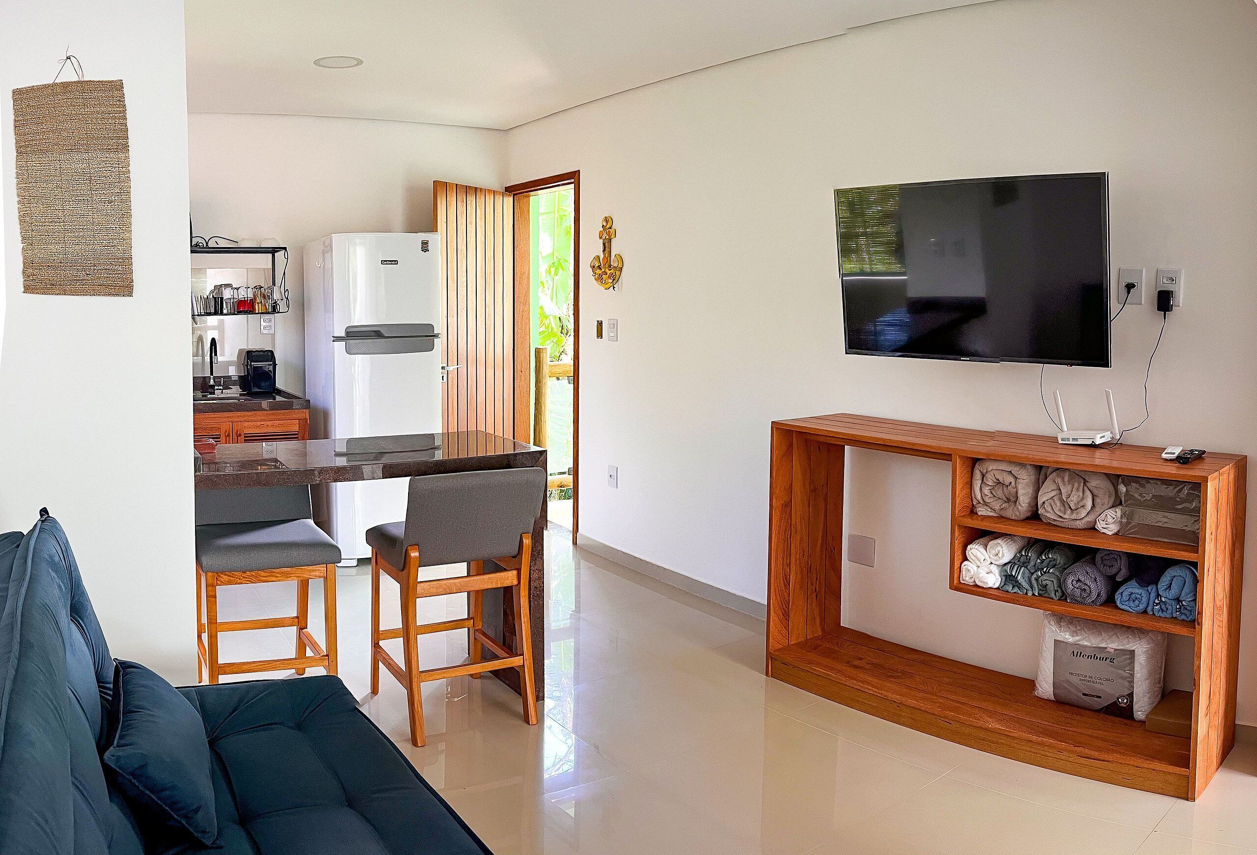 Un salón moderno con un sofá, una mesa de centro de madera y un televisor sobre un mueble de madera.