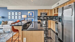 A modern kitchen with stainless steel appliances, wooden cabinets, and a black countertop.