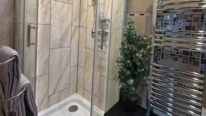 A modern bathroom with a glass-enclosed shower, a towel rack, and a small plant. - Studio C - Newly renovated private 1 bed studio (Gamston)