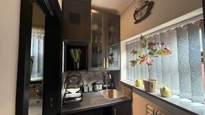 A compact kitchen with dark cabinetry, a sink, and a window with a view. - Studio C - Newly renovated private 1 bed studio (Gamston)