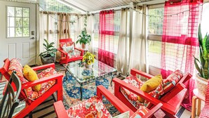 Une pièce avec une table basse en verre, des chaises rouges et une plante en pot.