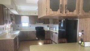 A kitchen with wooden cabinets, a black refrigerator, a stove, and a sink. - Beautiful home, huge  kitchen, strong Wi-Fi , lots of room, plenty of parking (Jewett)