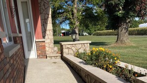A concrete pathway leading to a stone wall with a flower bed. - Beautiful home, huge  kitchen, strong Wi-Fi , lots of room, plenty of parking (Jewett)