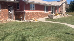 A two-story house with a brick facade, a stone chimney, and a front porch with a stone planter. - Beautiful home, huge  kitchen, strong Wi-Fi , lots of room, plenty of parking (Jewett)