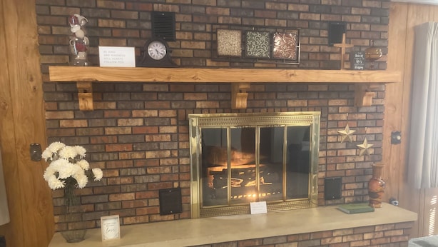 A brick fireplace with a glass door, a clock, and decorative items on the mantel. - Beautiful home, huge  kitchen, strong Wi-Fi , lots of room, plenty of parking (Jewett)