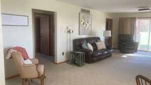 A living room with a brown leather sofa, a wooden armchair, a green side table, and a lamp. - Beautiful home, huge  kitchen, strong Wi-Fi , lots of room, plenty of parking (Jewett)