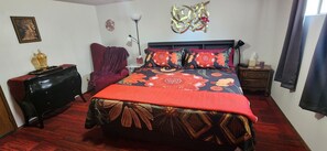 Une chambre à coucher comprenant un lit, une chaise, une commode, une table de chevet et une lampe.