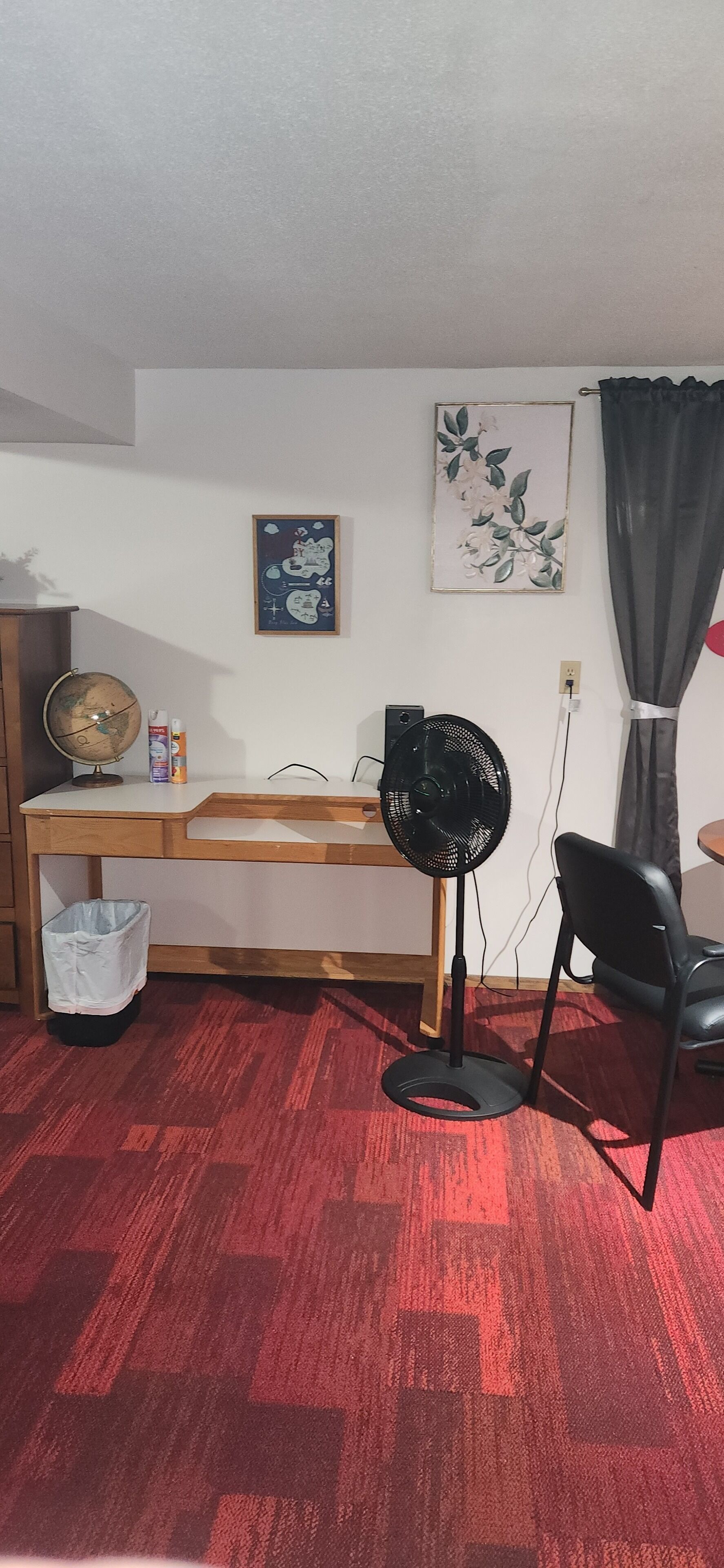 A room with a desk, a globe, a fan, and a chair.