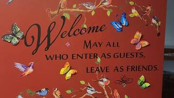A red wall with a welcome sign and decorative birds and butterflies.