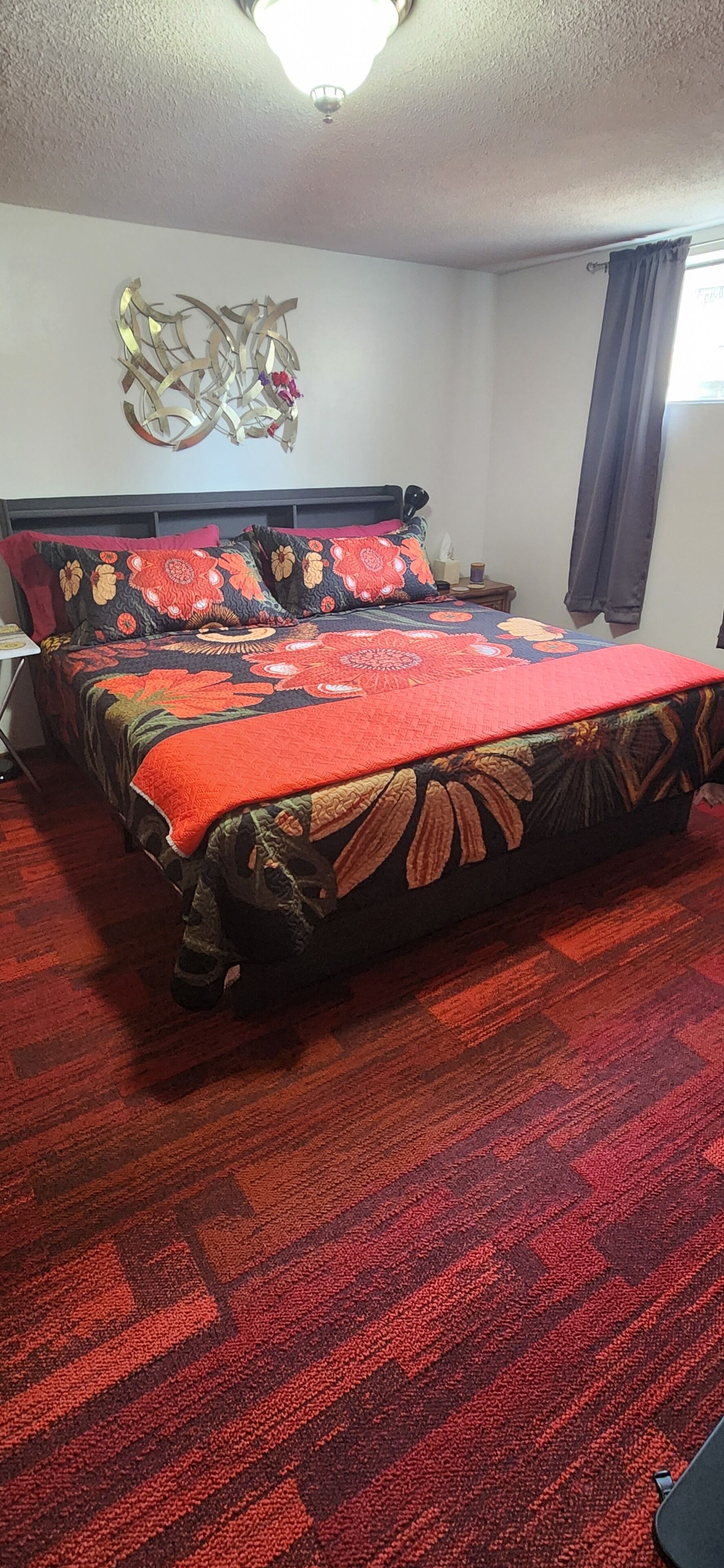 A hotel room with a large bed, a nightstand, a wall clock, and a ceiling light.