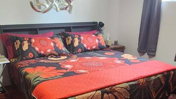 A hotel room with a large bed, a nightstand, a wall clock, and a ceiling light.