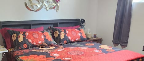 A hotel room with a large bed, a nightstand, a wall clock, and a ceiling light.