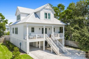 Ett vitt hus i två våningar med en balkong och en trappa som leder upp till övervåningen.