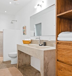 Ein modernes Badezimmer mit einem großen Spiegel, einem beige farbenen Waschbecken und einem Holzboden mit Handtüchern.