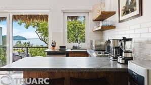 Una cocina moderna con una isla grande, vista al mar y un comedor.