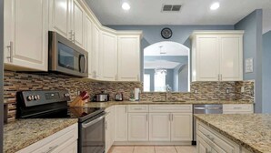 Una cocina con armarios blancos, microondas, estufa y lavavajillas.