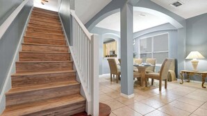 Una escalera con escalones de madera y barandillas blancas que conduce a un comedor con una mesa y sillas.