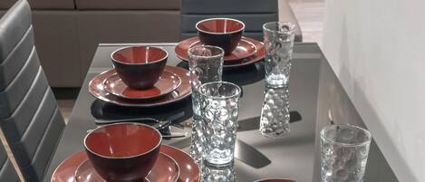 A dining table set with red bowls, plates, and clear glasses, with a black table runner.