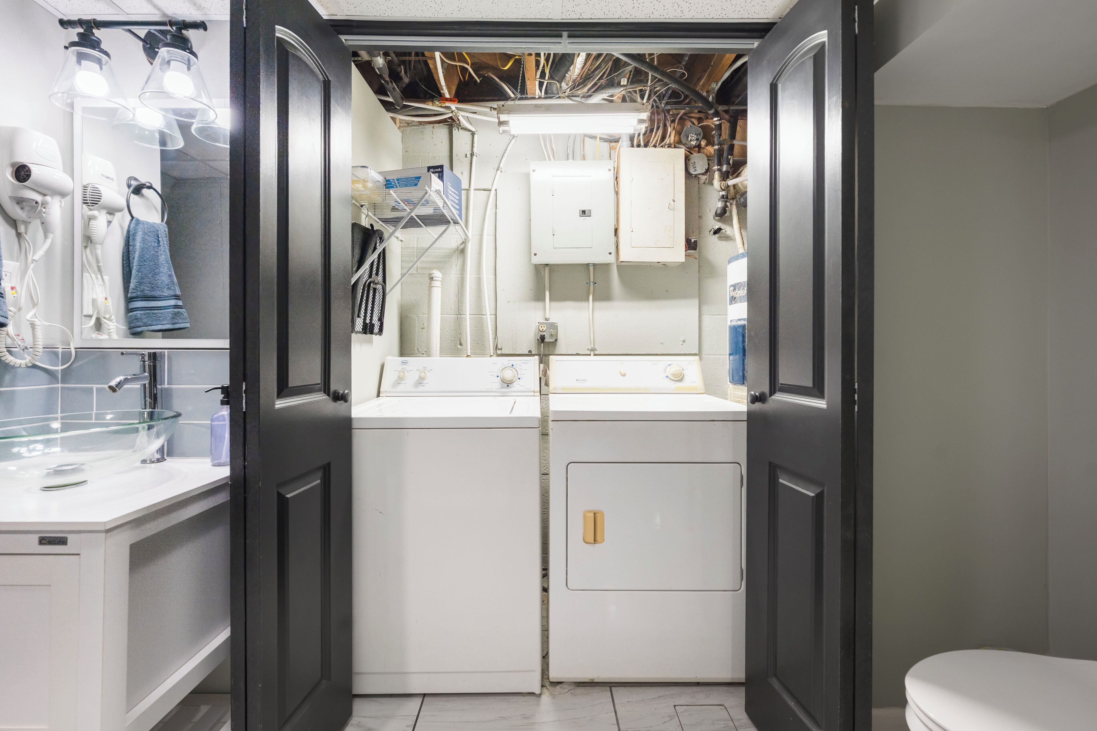 A compact laundry room with a washing machine, dryer, and a drying rack.