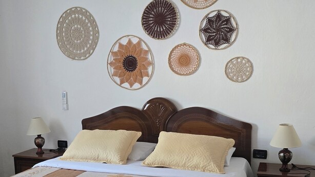 A neatly made bed with a floral bedspread, two bedside lamps, and a wall decorated with various circular patterns.