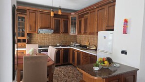 A kitchen with wooden cabinets, a white refrigerator, and a dining area with a table and chairs.