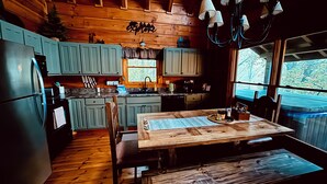 A cabin-style kitchen with wooden cabinets, a dining table, and a view of the outdoors.
