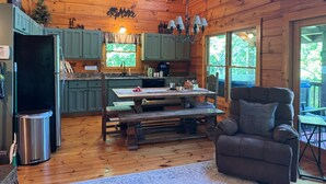 A wooden cabin interior with a kitchen, dining area, and seating space.