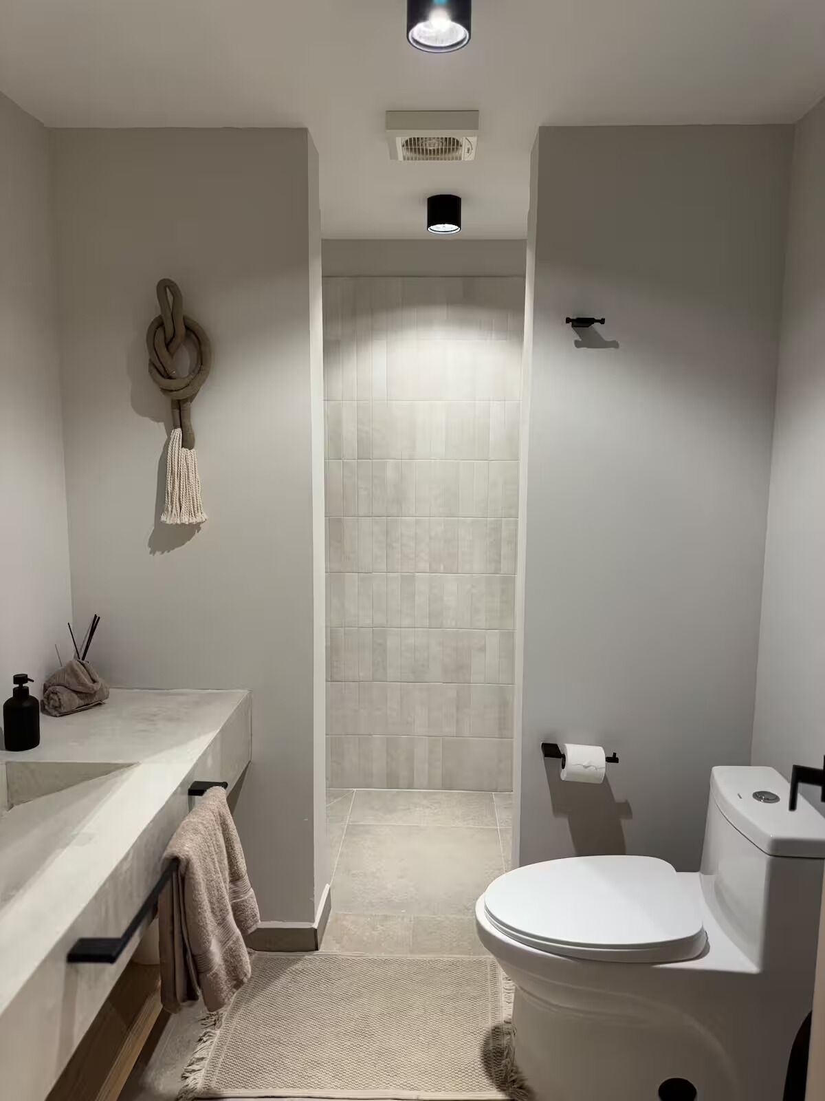 Een moderne badkamer met een wit wastafelmeubel, toilet en douchegedeelte.