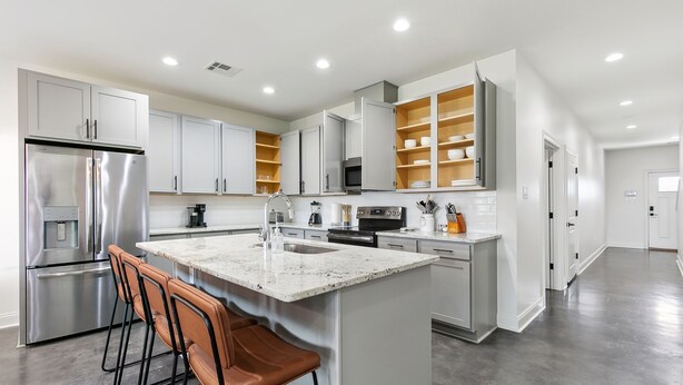 A modern kitchen with stainless steel appliances, white cabinetry, and a central island with bar stools. - Luxury 3BR in Belle Chasse (Belle Chasse)