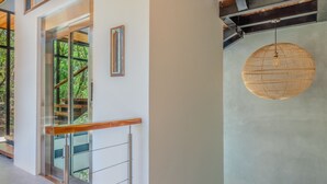 A modern interior with a glass railing, a hanging light fixture, and a wooden ceiling beam. - Villa Enlightened/Ocean View/Walk to Beach (Nosara)