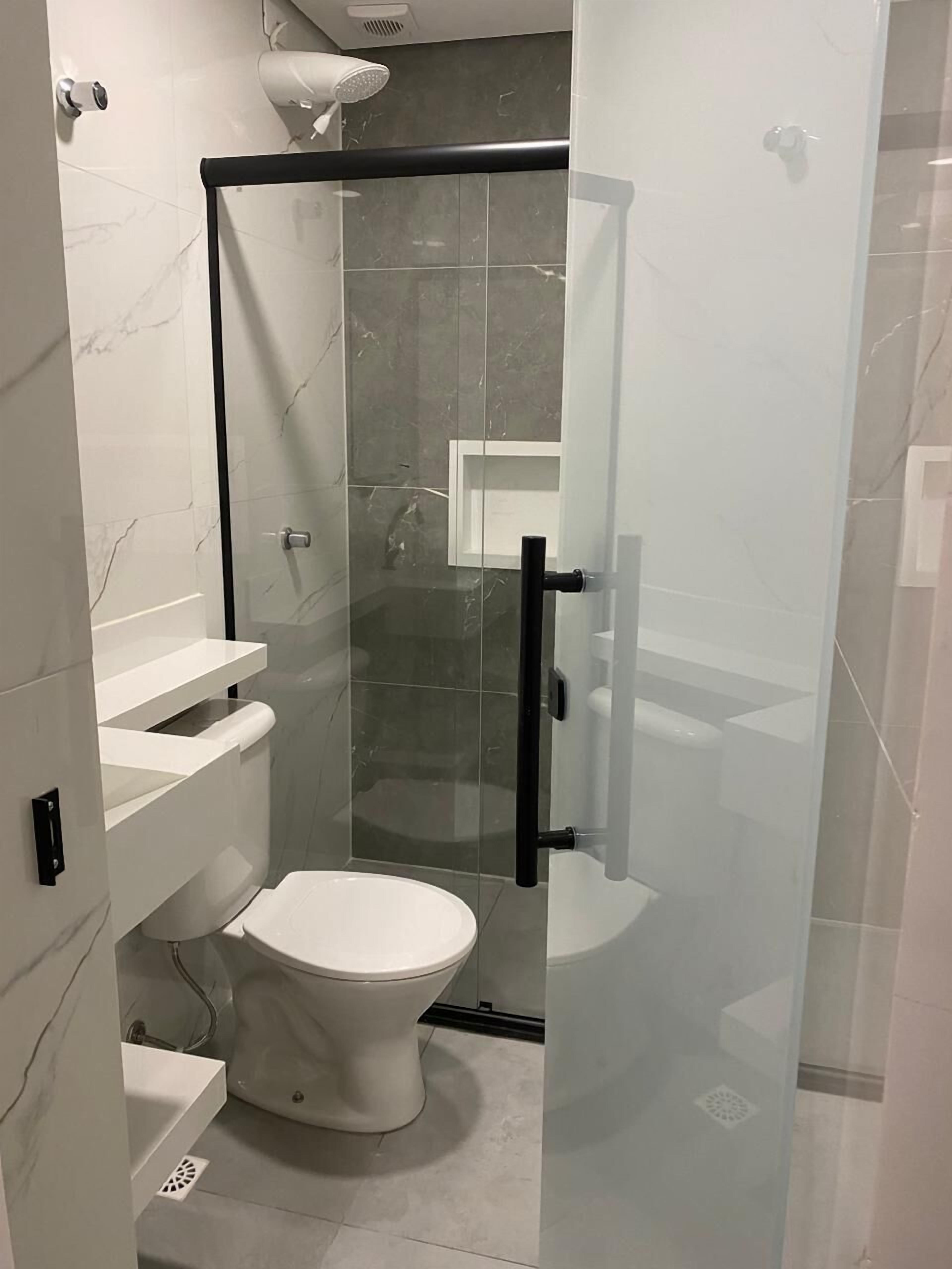 Un baño moderno con ducha de vidrio, inodoro y lavamanos.