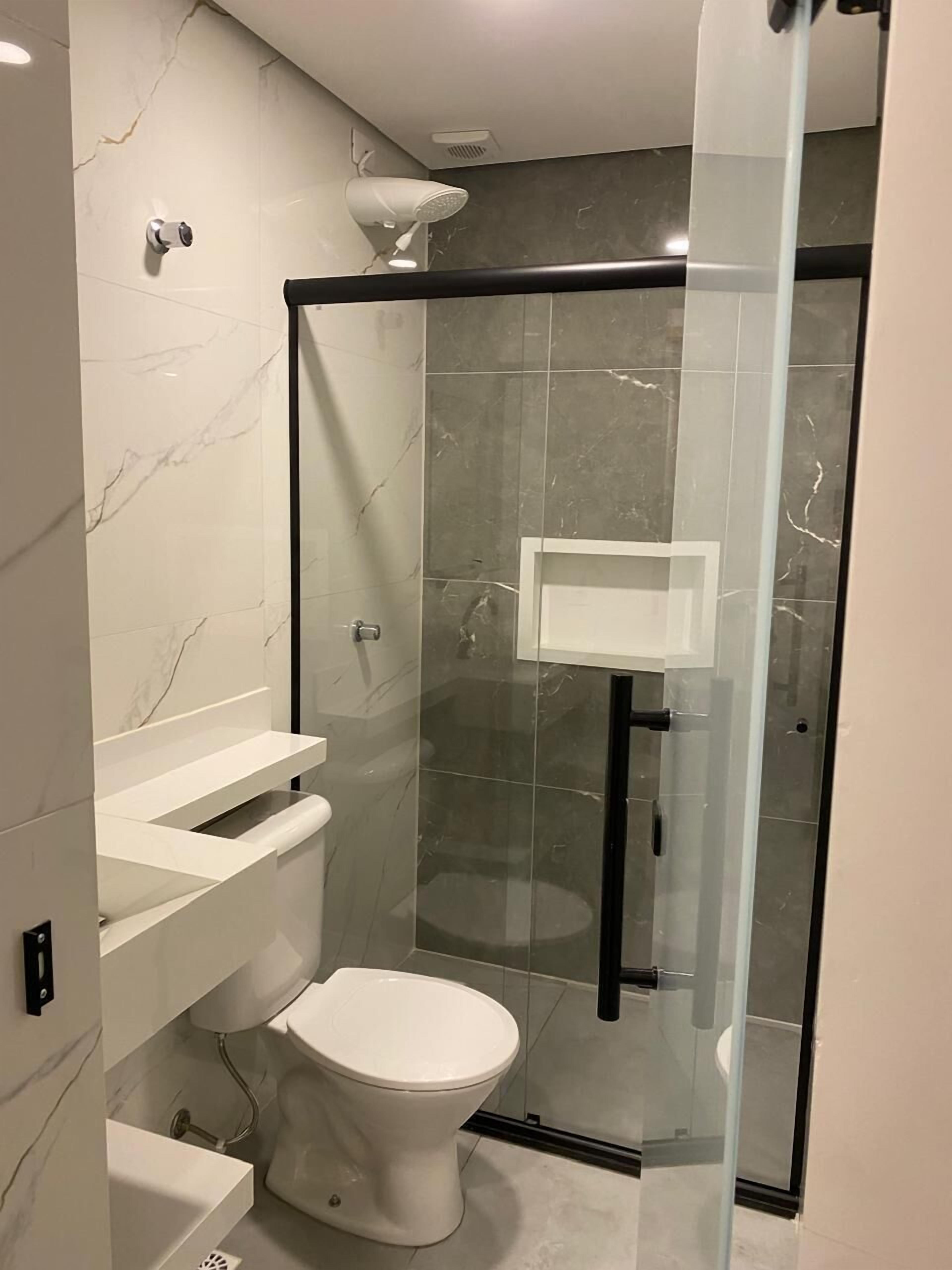 A modern bathroom with a glass-enclosed shower, a white toilet, and a vanity with a mirror.