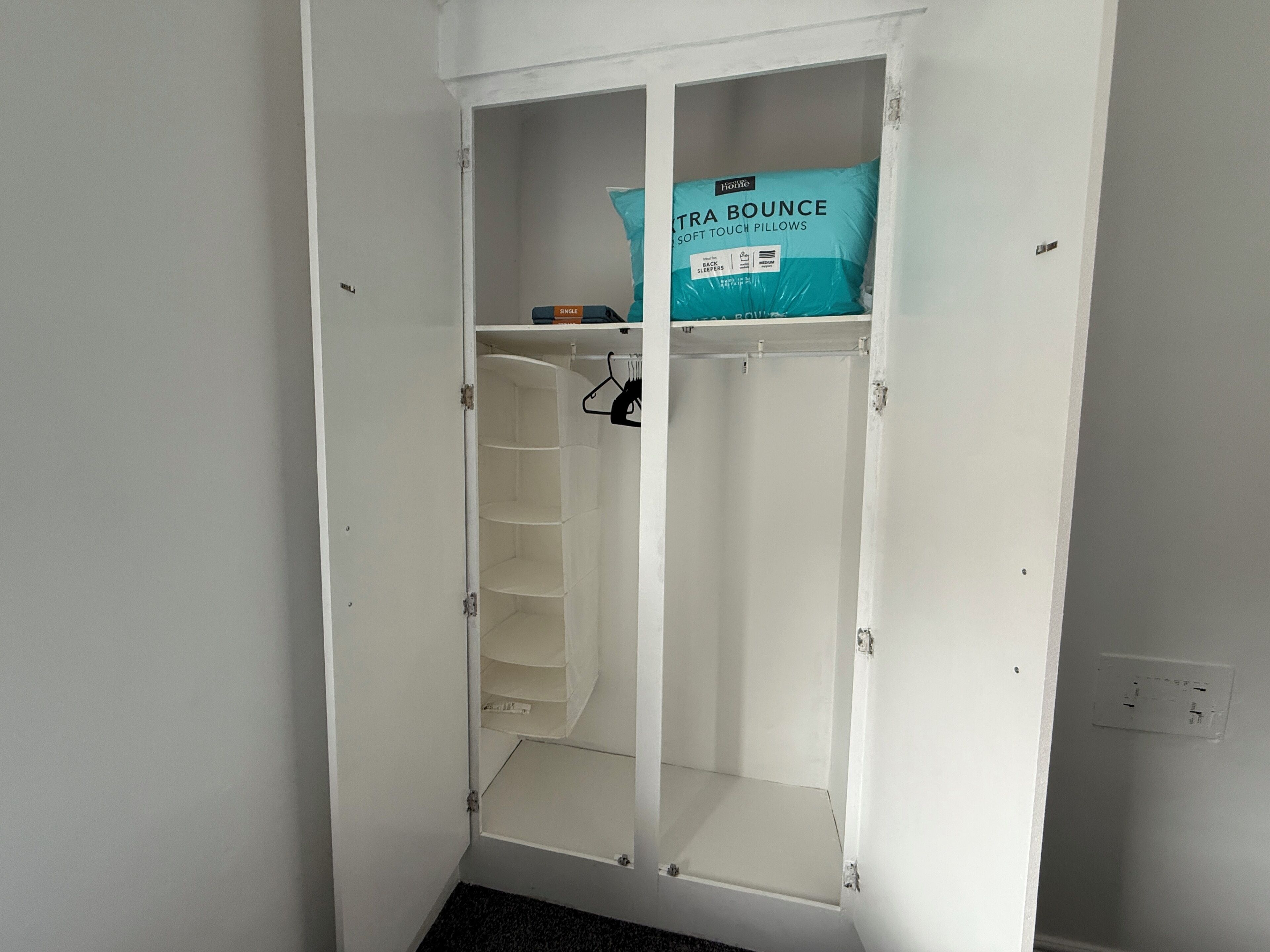 A white wardrobe with a single hanging space and a shelf.